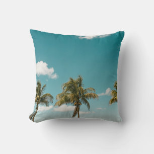 Green palm tree under blue sky in the morning throw pillow