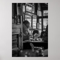 GREYSCALE PHOTO OF MAN SITTING WHILE READING NEWSP
