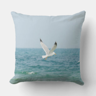 Gull flying above sea throw pillow