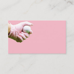 Hand in pink glove is holding golf ball business card