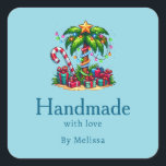 Handmade with Love Tropical Christmas Palm Tree Square Sticker<br><div class="desc">Handmade with Love product stickers with a seasonal holiday image. A tropical palm tree decorated in festive lights with a star on top. A giant red and white candy cane sticking out of the sand. Christmas presents under the tree. Whimsical and fun.</div>