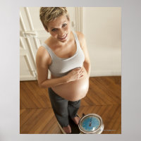 Happy pregnant woman standing on scale