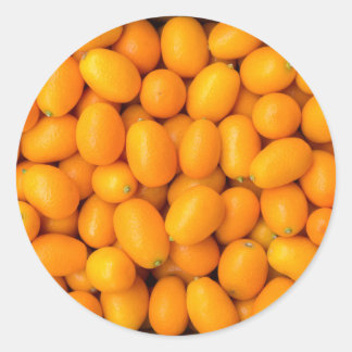 Heap of orange kumquats in cardboard box classic round sticker