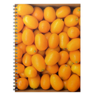 Heap of orange kumquats in cardboard box notebook