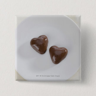 Heart shaped chocolate candies on a plate 2 inch square button