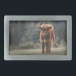Highland cow calf autumn grass field belt buckle<br><div class="desc">Highland cow calf autumn grass field photograph. Stunning young calf of highland Scottish cattle on an autumn grassy field with muted colours. Beautiful dark hairy orange coat contrasting with light yellow green grass and trees in bokeh in background.</div>