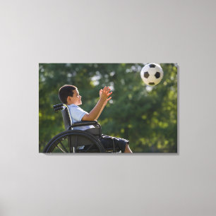 Hispanic boy, 8, in wheelchair with soccer ball canvas print