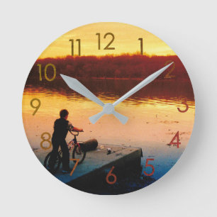 Horloge murale garçon à vélo au coucher du soleil
