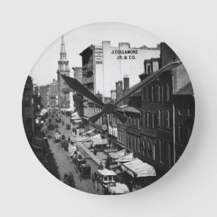 Horloge Ronde 1859 : Le trafic et magasins sur la rue de