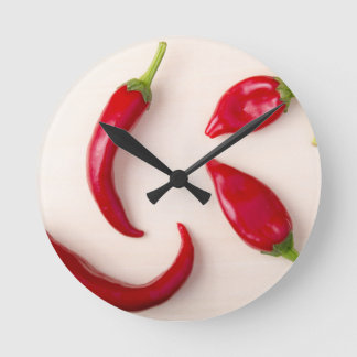 Horloge Ronde Piments rouges chauds sur une planche en bois clai