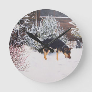 Horloge Ronde Winter snow scene with cute black and tan dog