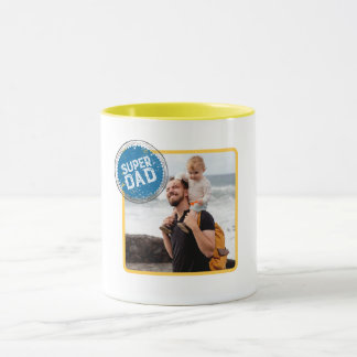 Image of a man carrying a child with "super dad" mug