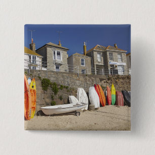 Kayaks and dinghies stacked against seawall at 2 inch square button
