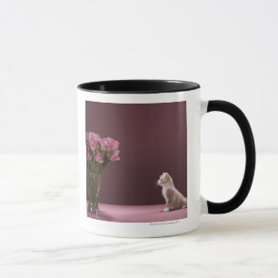 Kitten looking at vase of roses mug
