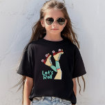 Let’s Roll Girls | Fun Retro Roller Skate Girl T-Shirt<br><div class="desc">The T-shirt design features a vibrant retro-inspired illustration of a girl’s legs wearing vintage-style roller skates with red boots and teal laces, paired with striped knee-high socks in shades of white and aqua. The phrase "Let’s Roll" is displayed in playful turquoise typography, complementing the lively energy of the design. Making...</div>