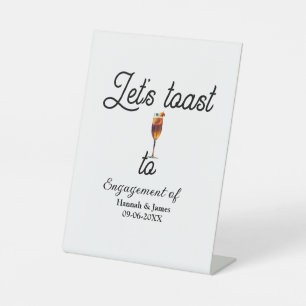 Let's toast to engagement party name date glass pedestal sign