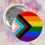 LGBTQ & Pride - Rainbow Progress Flag 1 Inch Round Button<br><div class="desc">Button: Rainbow Flag & the "Progress" variation adds a chevron along the hoist that features black, brown, light blue, pink, and white stripes to bring those communities (marginalized people of colour, trans individuals, and those living with HIV/AIDS and those who have been lost) to the forefront; "the arrow points to...</div>