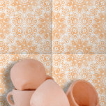 Light Orange White Ornate Symmetrical Geometric Tile<br><div class="desc">This ceramic tile features an intricate design that is both symmetrical and sophisticated. The design is characterized by ornate, white floral and geometric shapes that contrast beautifully against a warm, peach-coloured background. The tile's design is centred around a diamond-shaped element, surrounded by elegant swirls and curves. This central motif is...</div>