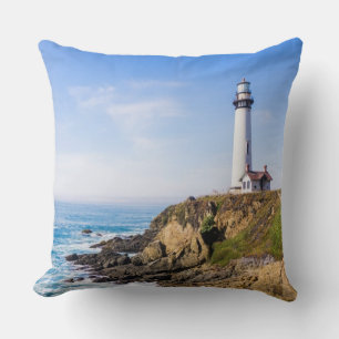 Lighthouse on hill blue sky white house ocean throw pillow