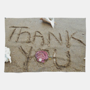 Linge De Cuisine Merci dans les coquilles et la plage de sable