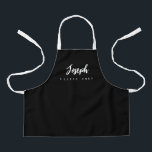 Little Chef Script Name personalized Black Apron<br><div class="desc">Make your little chef feel extra special with our Little Chef Script Name Personalized Kids black Apron. This apron is designed to provide a simple, chic, and elegant look, featuring stylish script typography for personalizing the name. The purple background colour adds a touch of vibrancy and fun, perfect for engaging...</div>