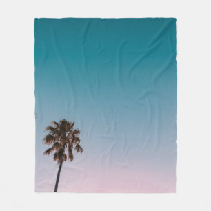 Low-angle photograph of three palm trees under blu fleece blanket