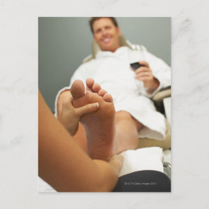 Low angle view of man receiving foot massage postcard