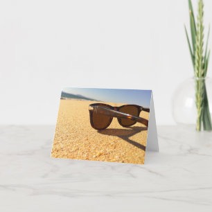 Lunettes de soleil sur la carte blanche de plage
