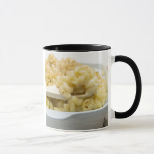 Macaroni cheese in baking dish with wooden mug