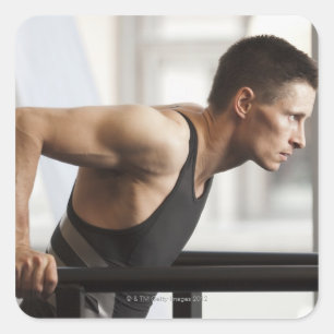 Male athlete using gymnastics equipment in gym square sticker