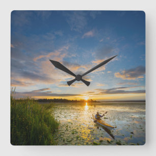 Male kayaker paddling sea kayak on still water square wall clock