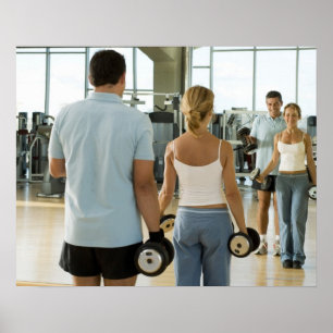 Man and woman lifting hand weights in front of a poster