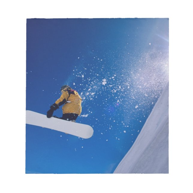 Man flying through the air on a snowboard with notepad (Front)