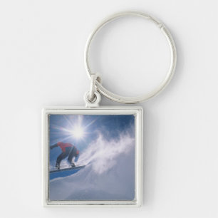 Man jumping off a large cornince on a snowboard keychain