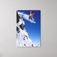 Man on a snowboard jumping off a cornice at