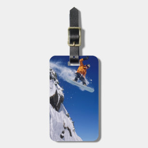 Man on a snowboard jumping off a cornice at luggage tag