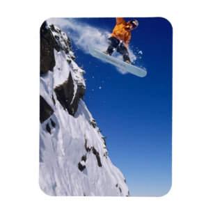 Man on a snowboard jumping off a cornice at magnet