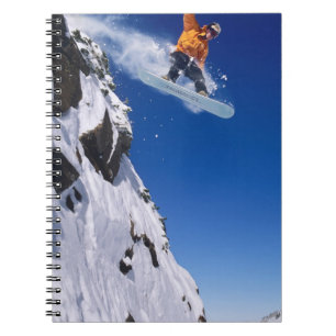 Man on a snowboard jumping off a cornice at notebook