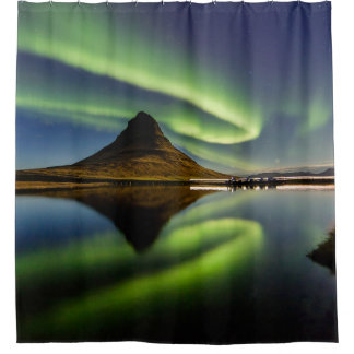 MAN STANDING BESIDE THE BODY OF WATER WITH AURORA