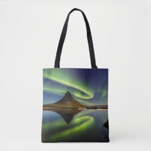 MAN STANDING BESIDE THE BODY OF WATER WITH AURORA TOTE BAG