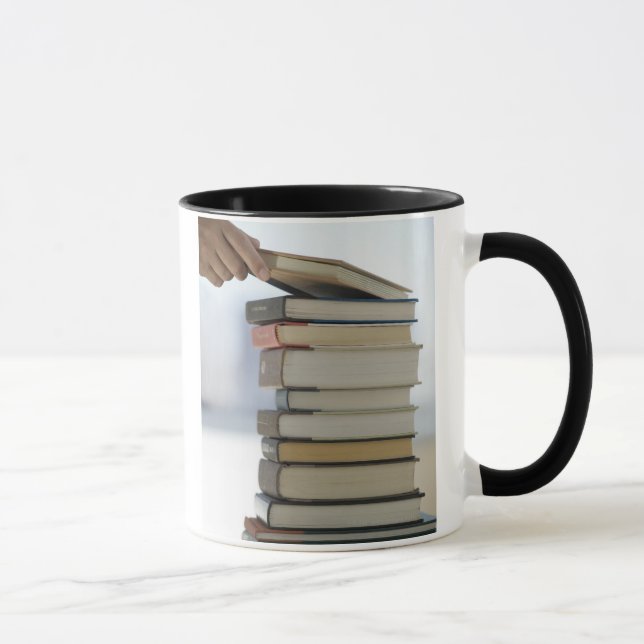 Man's hand taking a book from a stack of books mug (Right)