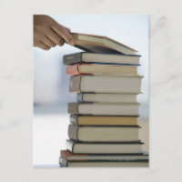 Man's hand taking a book from a stack of books
