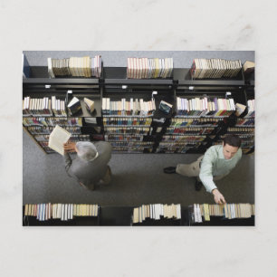 Men in library looking for books postcard