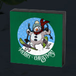Merry Christmas! Editable Text Skiing Snowman Wooden Box Sign<br><div class="desc">A festive decoration for your wall at Christmas, featuring a cartoon of a jolly snowman with a carrot nose and coal eyes, dashing through the snow on skis, in woolly winter hat and tartan scarf. An upbeat image for Xmas or throughout the winter. Use "Personalise this template" to change the...</div>