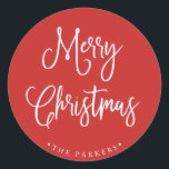 Merry Christmas | Handwritten Script on Red Classic Round Sticker<br><div class="desc">This simple and trendy holiday sticker says "Merry Christmas" in rustic,  white handwritten script on a bright,  holiday red background.</div>