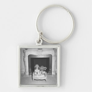 Miniature poodles sitting in front of fireplace keychain