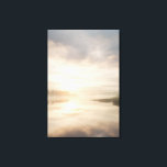 Misty Lake Sunrise Golden Reflection Canvas Print<br><div class="desc">Soft golden sunlight pierces through thick morning mist over a calm lake, creating a luminous path of reflection across the water. Tall reeds line the shore while distant trees fade into the haze, and the sky blends warm peach and rose tones into pale blue-gray. The composition radiates profound stillness, gentle...</div>