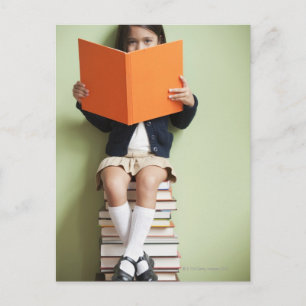 Mixed race girl sitting on stack of books postcard