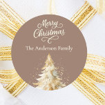 Mocha cream beige tree Christmas Classic Round Sticker<br><div class="desc">A mocha, muted brown coloured background. Decorated with a snowcovered tree. Merry Christmas is written with an elegant hand-lettered style script. Personalize and add your family name. Cream, beige coloured text.</div>