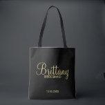 Modern Black and Gold Personalized Bridesmaids Tote Bag<br><div class="desc">Modern Black and Gold Personalized Bridesmaids Gifts featuring personalized bridesmaid's name in gold modern script font style with title and wedding date in modern sans serif font style on black background. Also perfect for Maid of Honour, Flower Girl, Mother of the Bride and more. Please Note: The foil details are...</div>